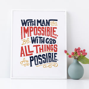 Artwork in a white frame with the artwork printed on white paper and hand drawn lettering with the Matthew 19:26 Bible verse reading "With man this is impossible but with God all things are possible."  The lettering is in navy, red and mustard yellow. 