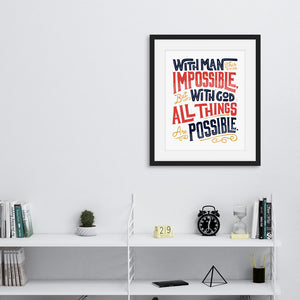 Artwork featured on a wall in a black from above a shelving unit. The artwork is on white paper and features hand drawn lettering with the Matthew 19:26 Bible verse reading "With man this is impossible but with God all things are possible."  The lettering is in navy, red and mustard yellow. 