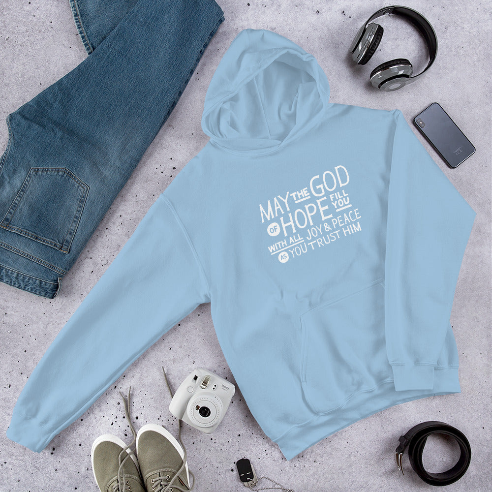 A light blue hoodie laying on the ground with objects around it. The hoodie features hand drawn lettering in white with the words 