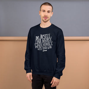 A man wearing a navy sweatshirt with white lettering featuring Do justly, love mercy, walk humbly, with your God, Micah 6:8.