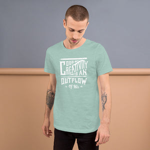 A man wearing a Heather Prism Dusty Blue short sleeved t-shirt. The tee features hand drawn lettering featuring the words "Our creativity is an outflow of His" in white letters.  