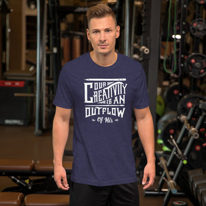 A man wearing a heather midnight blue color short sleeved t-shirt. The t-shirt features hand drawn lettering in white with the words "Our creativity is an outflow of His."