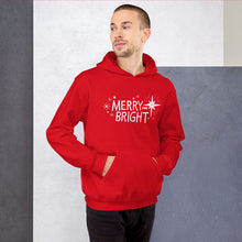 Load image into Gallery viewer, A man wearing a red hoodie featuring hand drawn lettering in white with the words &quot;Merry and Bright&quot; with white illustrated stars around the words. 
