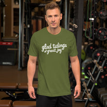 Load image into Gallery viewer, A man wearing an olive green short sleeved t-shirt. The tee features lettering of the words &quot;glad tidings of great joy.&quot; The words are in white. 