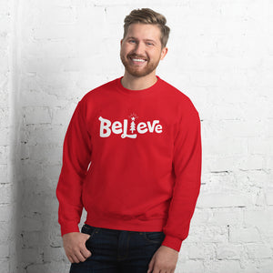 A man wearing a red sweatshirt featuring hand drawn lettering with the word Believe. The "I" of the word Believe is an illustrated Christmas tree. 