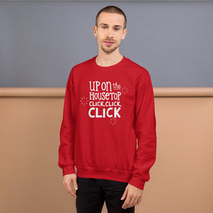 A man wearing a red sweatshirt featuring hand drawn lettering with the words "Up on the housetop, click, click, click" in white. There are three white stars around the words. 