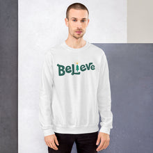 Load image into Gallery viewer, A man wearing a white sweatshirt featuring hand drawn lettering with the word Believe in green. The &quot;I&quot; of the word Believe is an illustrated Christmas tree. 
