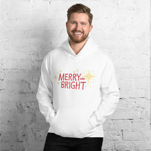 Load image into Gallery viewer, A man wearing a white hoodie featuring hand drawn lettering in red with the words &quot;Merry and Bright&quot; with yellow illustrated stars around the words. 