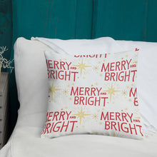 Load image into Gallery viewer, A white pillow with illustrations leading on white bedding with a side table off to the side. The white pillow features illustrated yellow stars and the words Merry and Bright in red in a repeat pattern all over the pillow. 