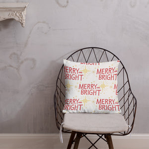 The pillow is leaning on a metal chair with a cushion. The white pillow features a Christmas pattern of yellow illustrated stars and the red words of Merry and Bright. 
