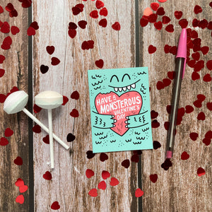 A classroom valentine reading "Have a monsterous Valentine's Day." It's laying on a table top with heart confetti.