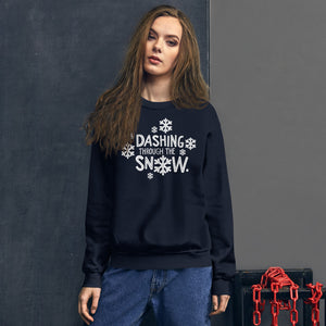 A woman wearing a navy blue sweatshirt featuring hand drawn lettering with the words "Dashing through the snow" in white. There are snowflakes around the words. 