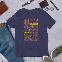 Load image into Gallery viewer, A navy short sleeved T-shirt laying flat with objects around it. The T-Shirt features hand lettering with the CS Lewis quote &quot;Once a king or queen of Narnia, always a king or queen of Narnia.&quot;