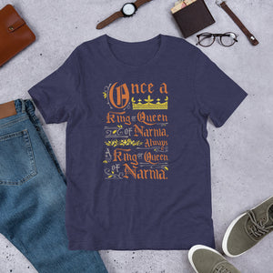 A navy short sleeved T-shirt laying flat with objects around it. The T-Shirt features hand lettering with the CS Lewis quote "Once a king or queen of Narnia, always a king or queen of Narnia."