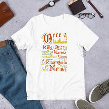 Load image into Gallery viewer, A white short sleeved T-shirt laying flat with objects around it. The T-Shirt features hand lettering with the CS Lewis quote &quot;Once a king or queen of Narnia, always a king or queen of Narnia.&quot;