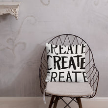 Load image into Gallery viewer, A pillow on a chair against a grey wall. The pillow is white and features the words “create, create, create&quot; in black lettering with each word in three different fonts. 