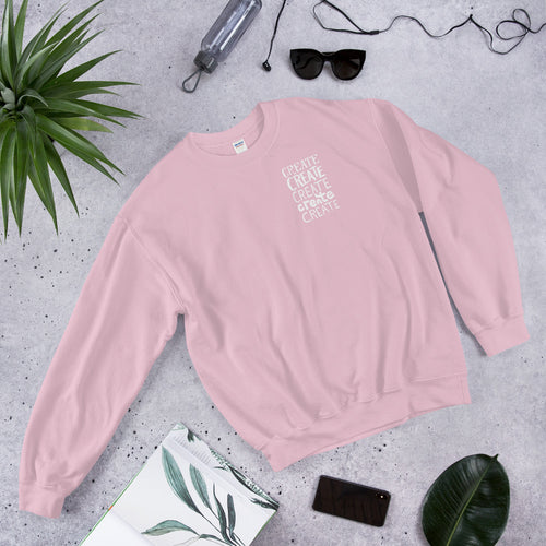 A light pink sweatshirt laying with jeans and shoes. The pink sweatshirt features the word 