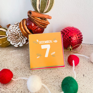 A close up photo of one of the Advent cards showing the number of that day. In the background on the mantle is a candle and some Christmas decor.
