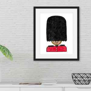 A black from on a white brick wall with an illustration of a queen's guard inside the frame. The frame is featured above a white sideboard. 