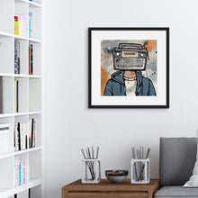 Load image into Gallery viewer, A black framed print hanging on a wall above the corner of a sofa and next to a set of bookshelves. The artwork in the frame features a boombox as a head on a person wearing a blue hoodie. 