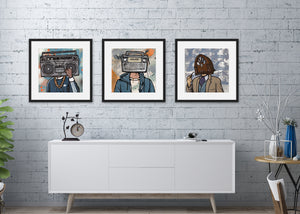 Three black framed prints featuring vintage radios as "heads" on people. The frames are featured above a white cabinet. 