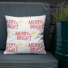 Load image into Gallery viewer, The white pillow is leaning on a sofa with a plant off to the side. The pillow is white with Christmas star illustrations in yellow and the words Merry and Bright in red. 