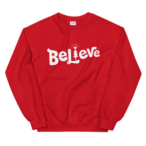 A red sweatshirt on a white background. The sweatshirt features the word Believe in white with the "I" of Believe as an illustrated Christmas tree. 