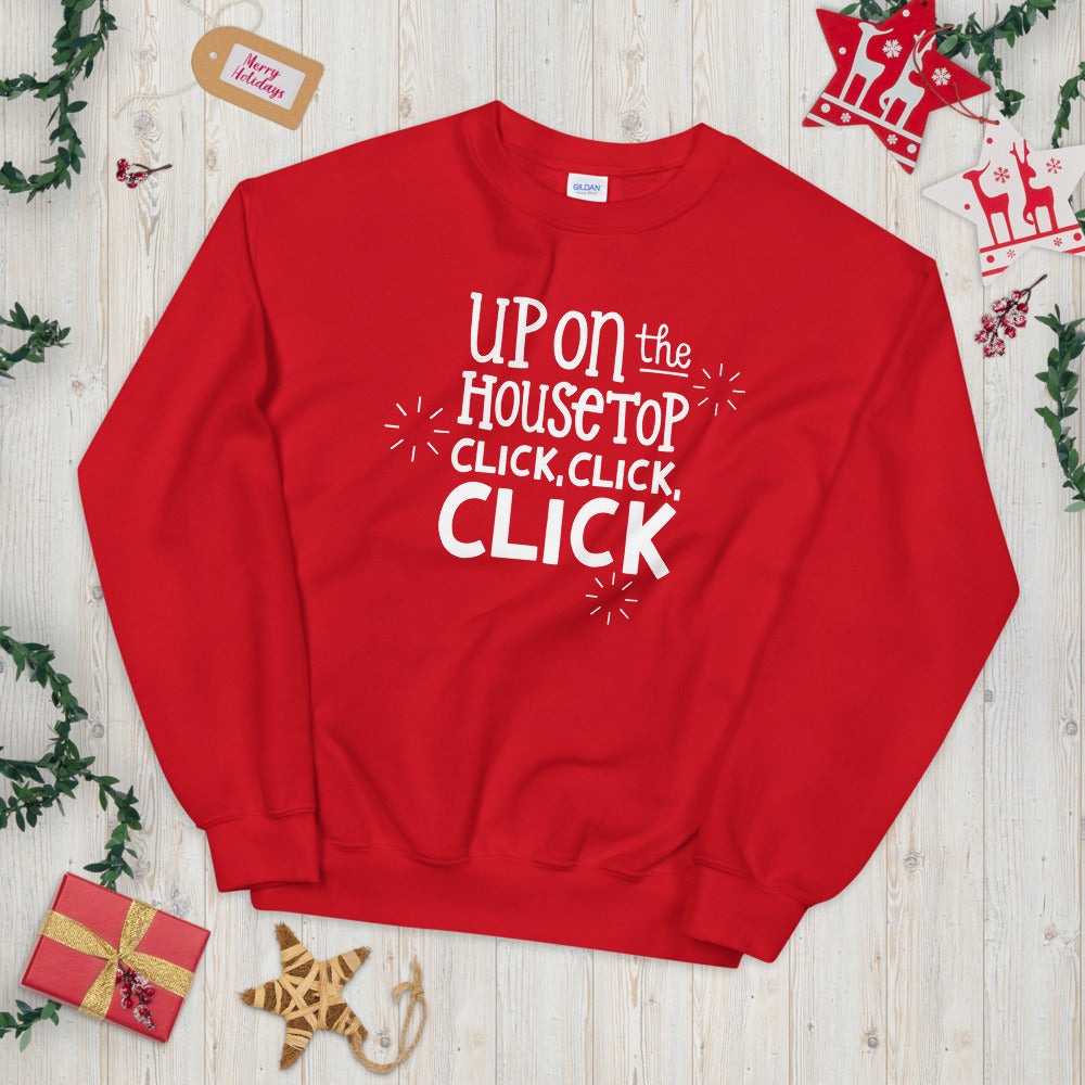 A red sweatshirt laying on a table with Christmas objects around it. The sweatshirt features the words 