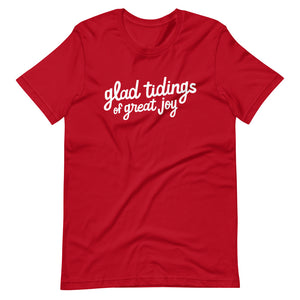 A red T-shirt on a white background. The navy shirt features words in white reading "glad tidings of great joy" in white. 