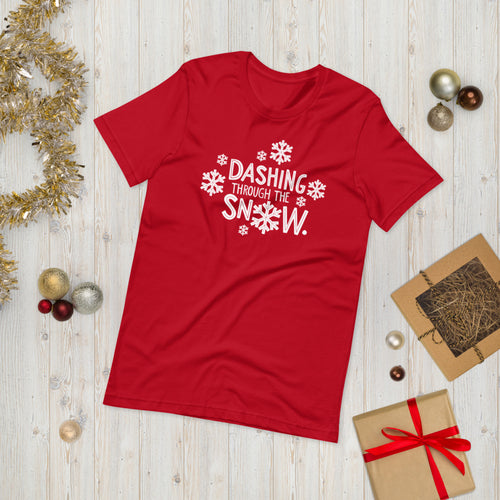 A red T-shirt laying on the ground with Christmas items surrounding it. The T-shirt features the words  