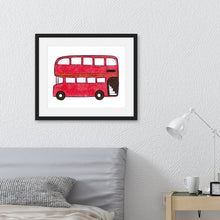 Load image into Gallery viewer, An illustration of a red, double decker bus in a black frame. The frame is hanging on the wall above a bed with a grey headboard.