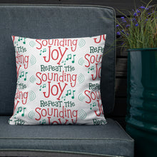 Load image into Gallery viewer, The white pillow is leaning on a sofa with a plant off to the side. The pillow is white and has the words in red and green saying &quot;Repeat the sounding joy.&quot; The words are repeated in a pattern with musical notes all over the pillow. 