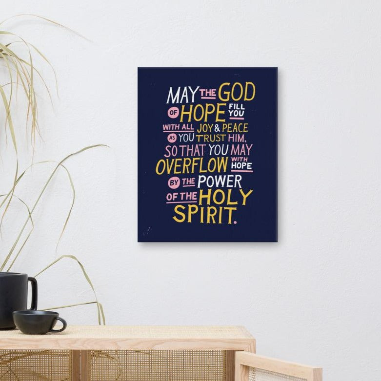 A canvas shown on a wall above a shelf. The canvas is purple and features hand drawn text in white, pink and yellow reading 