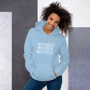 A woman wearing a light blue hoodie featuring hand drawn lettering in white with the words "May the God of hope fill you with all joy and peace as you trust him."
