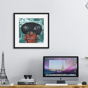 A black frame above a desk with a computer. The frame features illustrated artwork of an orignial Sega Genesis controller as someone's "head."