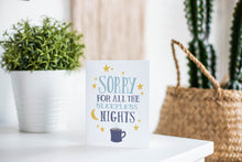 Load image into Gallery viewer, A greeting card is featured on a white tabletop with a white planter in the background with a green plant. There’s a woven basket in the background with a cactus inside. The card features the words “Sorry for all the sleepless nights.”