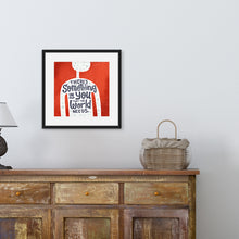 Load image into Gallery viewer, A red print in a black frame hangs on a pale living room wall. The print features the outline of a person in white, filled with light grey doodles. The words ‘There’s something in you the world needs&#39; are lettered in black across the person’s chest. Beneath the print there&#39;s a wooden sideboard, with a lamp and basket on top.