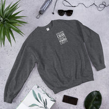 Load image into Gallery viewer, A dark grey sweatshirt laying with jeans and shoes. The dark grey sweatshirt features the word &quot;create, create, create, create, create&quot; in white in a small rectangle on the upper left side.