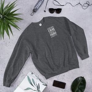 A dark grey sweatshirt laying with jeans and shoes. The dark grey sweatshirt features the word "create, create, create, create, create" in white in a small rectangle on the upper left side.