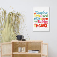 Load image into Gallery viewer, A canvas shown on a wall above a shelf. The canvas features the phrase “A teacher takes a hand, opens a mind, and touches a heart.” The “a” in the word “heart” is a heart shape and the words are blue, red, yellow and green. 
