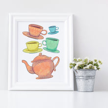 Load image into Gallery viewer, Artwork in a white frame with the with a white matte. The frame is leaning on a shelf with a metal plant pot next to it with white flowers. The artwork is on a white background with four teacups on saucers and one large teapot. The teacups are in muted colors of orange, blue, yellow and green and the teapot is a muted orange. On the teacups, saucers and teapot there is a light flower detail pattern.