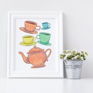 Artwork in a white frame with the with a white matte. The frame is leaning on a shelf with a metal plant pot next to it with white flowers. The artwork is on a white background with four teacups on saucers and one large teapot. The teacups are in muted colors of orange, blue, yellow and green and the teapot is a muted orange. On the teacups, saucers and teapot there is a light flower detail pattern.