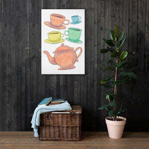 A canvas is hanging on a dark wood panelled wall with a basket with a blanket and a potted plant on the floor. The artwork is on a white background with four teacups on saucers and one large teapot. The teacups are in muted colors of orange, blue, yellow and green and the teapot is a muted orange. On the teacups, saucers and teapot there is a light flower detail pattern.