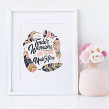 Load image into Gallery viewer, Artwork in a white frame with the with a white matte. The artwork is on a white background with lettering reading &quot;Tender Warriors Are Being Made Here&quot; The words are in pink, navy and dark mustard yellow. 