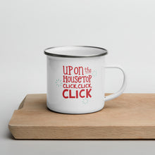 Load image into Gallery viewer, A white enamel mug sitting on top of a wood cutting board on a white background. The mug is white with the very top silver enamel. The design features the words &quot;Up on the housetop, click, click, click&quot; in red with small blue stars around the words. 