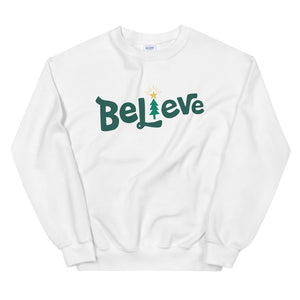 A white sweatshirt on a white background. The sweatshirt features the word Believe in green with the "I" of Believe as an illustrated Christmas tree. 
