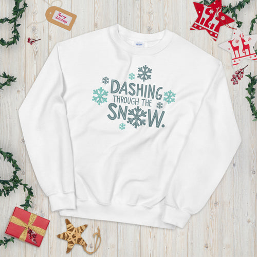 A white sweatshirt laying on a table with Christmas objects around it. The sweatshirt has the words 