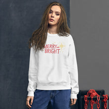 Load image into Gallery viewer, A woman wearing a white sweatshirt featuring hand drawn lettering in red with the words Merry and Bright. Around the words are yellow illustrated stars. 
