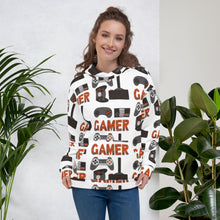 Load image into Gallery viewer, A woman wearing a white hoodie featuring different game controllers and the word &quot;gamer&quot; in a repeat pattern throughout the hoodie. The illustrations and gamer word are in red, grey and black. 