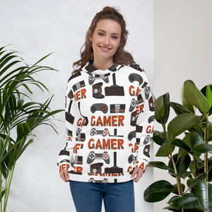 A woman wearing a white hoodie featuring different game controllers and the word "gamer" in a repeat pattern throughout the hoodie. The illustrations and gamer word are in red, grey and black. 